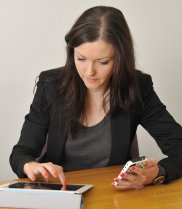 Woman seated at table using mobile devices.