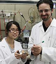 Ms Richelle Lyndon and Dr Matthew Hill standing in a laboratory holding a piece of equipment.