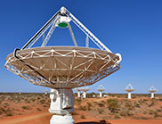 Close up of a radio astronomy telescope in the foreground with several more at distance in the background.