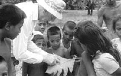 Doug Waterhouse showing children in Kiribati a scale insect infestation on a breadfruit leaf