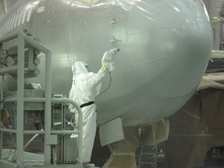 Worker in safety gear painting a jumbo jet