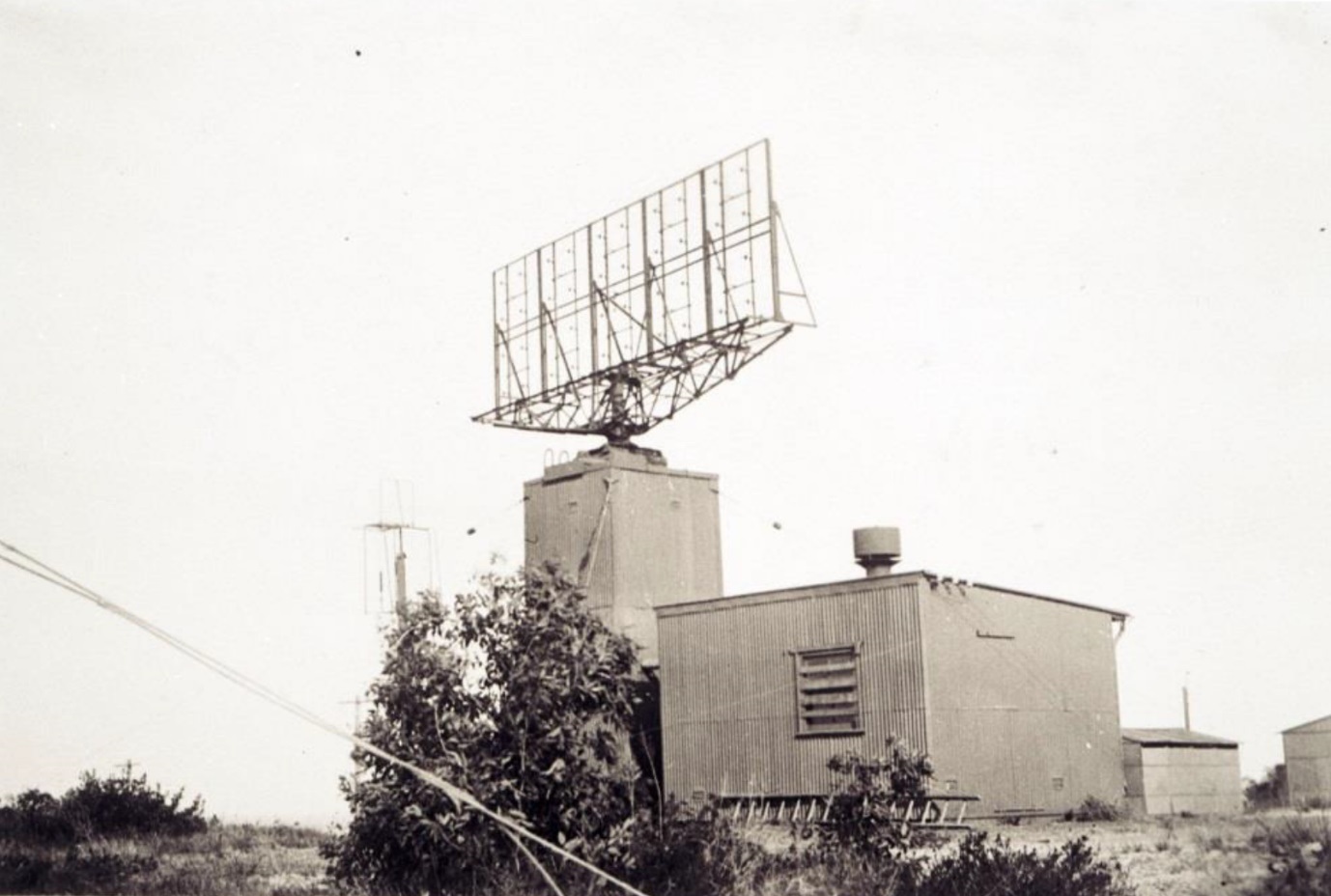 Black and white image of a building with a large antenna on the roof